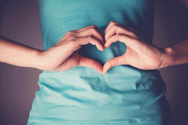 Woman hands making a heart shape on her stomach 1